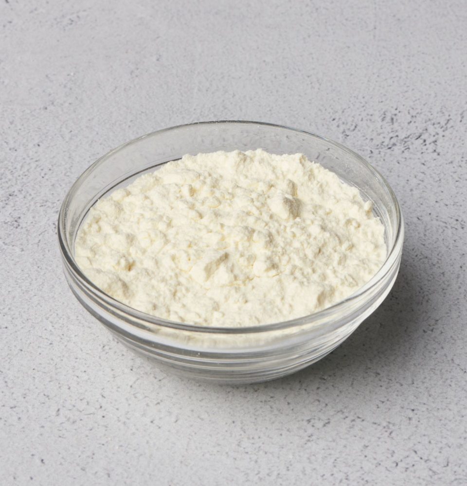 A clear glass bowl filled with milk protein concentrate powder, meant to replace nonfat and skim milk powder.