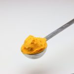 A silver tablespoon measuring cup full of cheese seasoning powder.